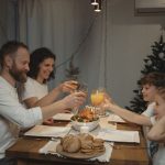 A joyful family toasting at a festive dinner table with festive decor indoors.